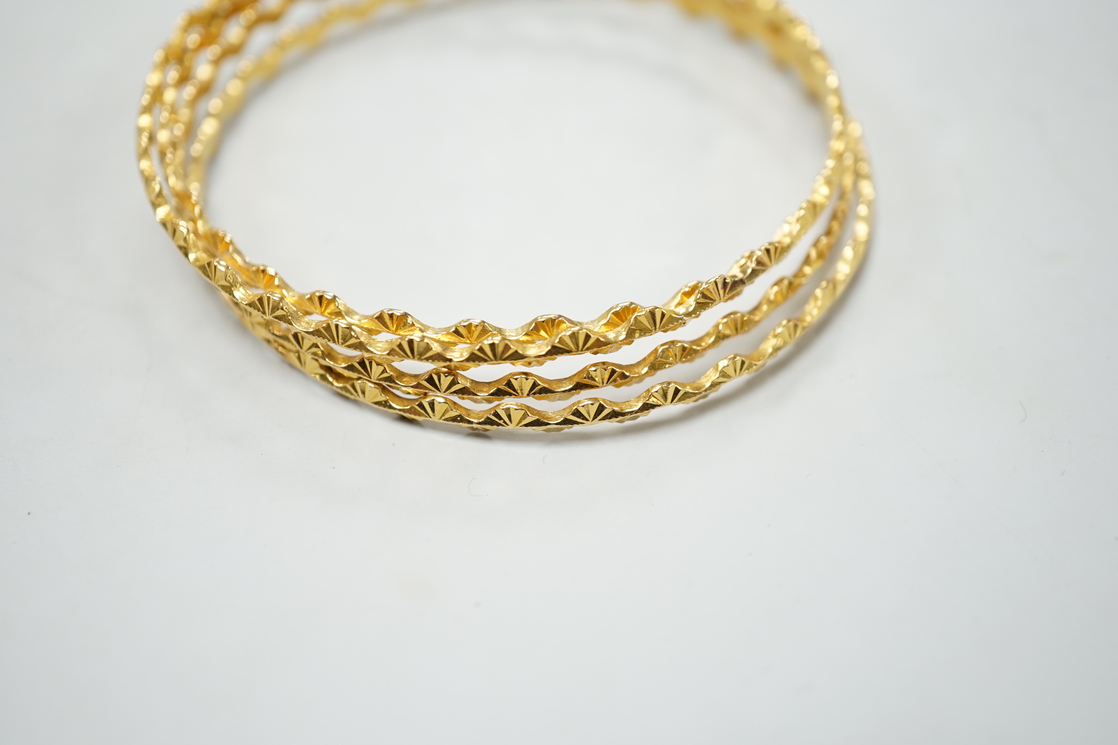 A set of four bright cut yellow metal bangles, with wavy border 34 grams.
